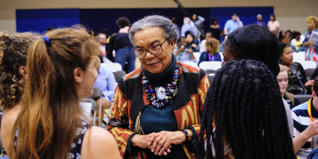 Marian Wright Edelman speaks with a group of young women at an event.