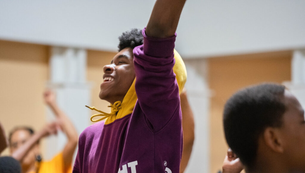 Young man dances and laughs during Harambee